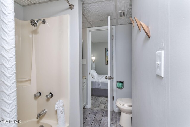 bathroom featuring bathtub / shower combination, toilet, and hardwood / wood-style flooring