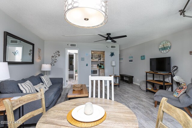 living room with hardwood / wood-style floors, ceiling fan, and a textured ceiling