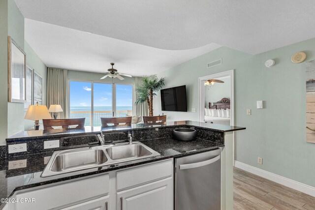 kitchen featuring stainless steel appliances, dark stone countertops, white cabinets, light hardwood / wood-style flooring, and sink