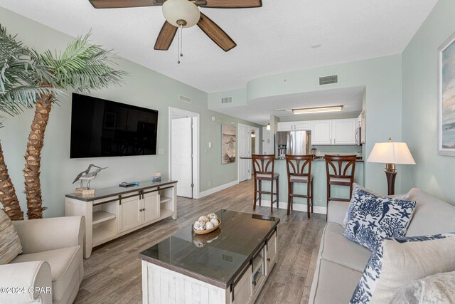 kitchen with stainless steel appliances, light hardwood / wood-style flooring, white cabinetry, and a breakfast bar