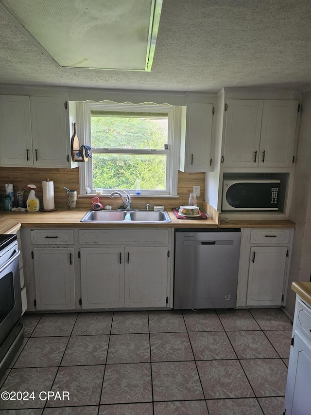 2510 W 18th St, Panama City, FL 32405 - kitchen featuring light tile patterned floors, white cabinetry, range with electric stovetop, dishwasher, and a sink