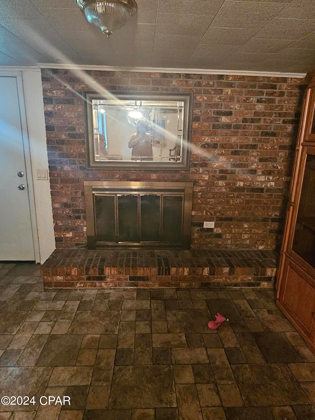 interior details featuring ornamental molding and a brick fireplace