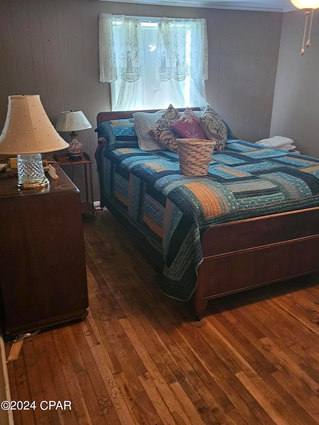 bedroom with wood walls and dark hardwood / wood-style flooring