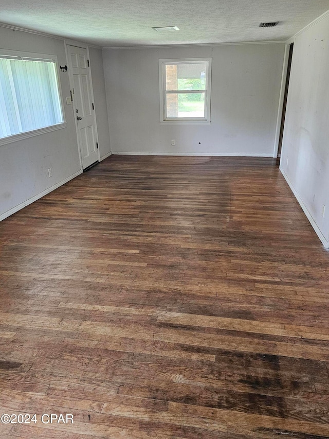 spare room featuring a textured ceiling and dark hardwood / wood-style floors