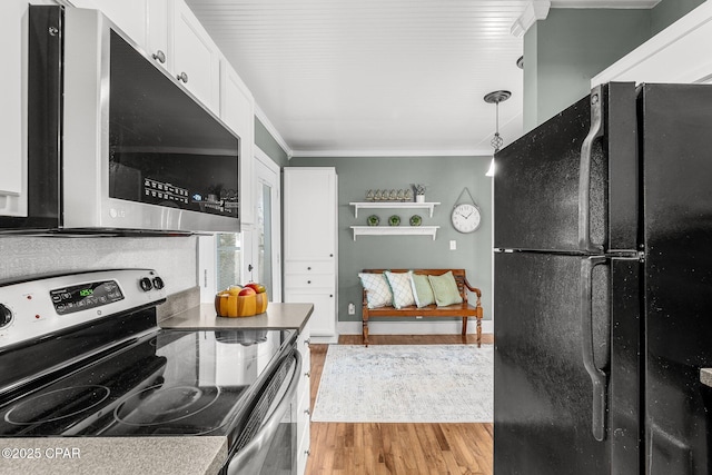 kitchen featuring pendant lighting, stainless steel appliances, ornamental molding, white cabinets, and light wood-type flooring