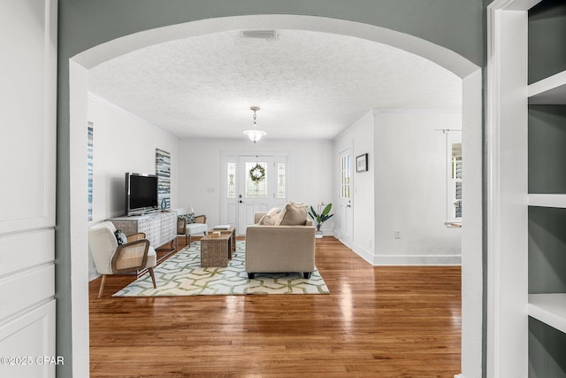 living room featuring crown molding, wood-type flooring, and a textured ceiling