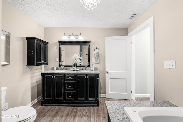 bathroom with vanity, toilet, hardwood / wood-style floors, and a textured ceiling