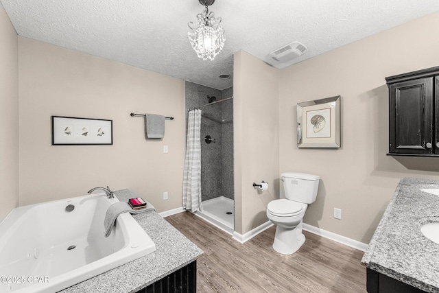 full bathroom with hardwood / wood-style flooring, vanity, separate shower and tub, toilet, and a textured ceiling