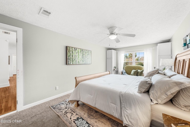 carpeted bedroom featuring ceiling fan and a textured ceiling