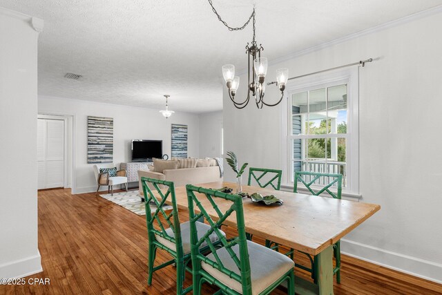 dining area featuring hardwood / wood-style flooring, a textured ceiling, and an inviting chandelier