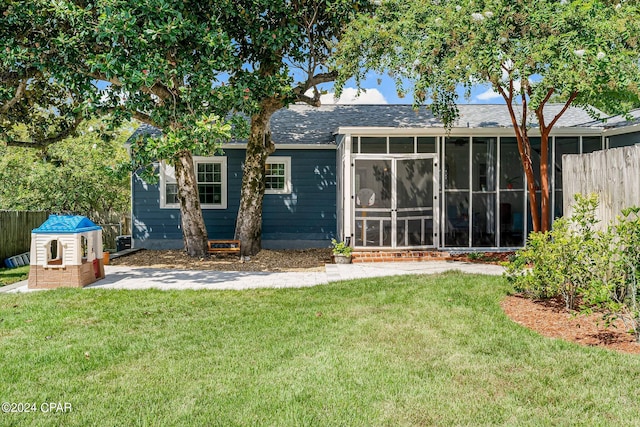 rear view of house with a yard and a sunroom