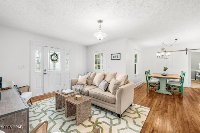 living room with crown molding, a barn door, a textured ceiling, and light hardwood / wood-style flooring