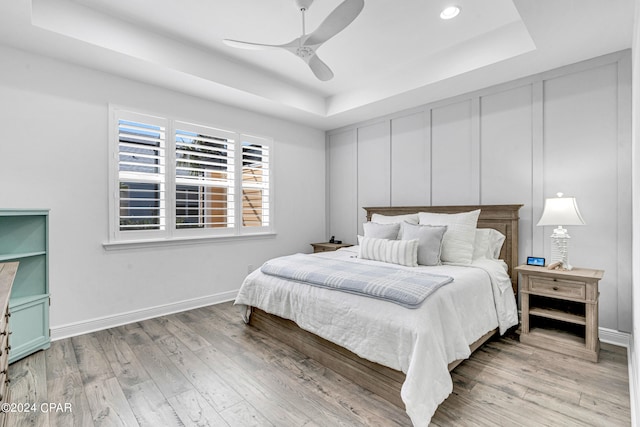 bedroom featuring a tray ceiling, ceiling fan, and light hardwood / wood-style floors