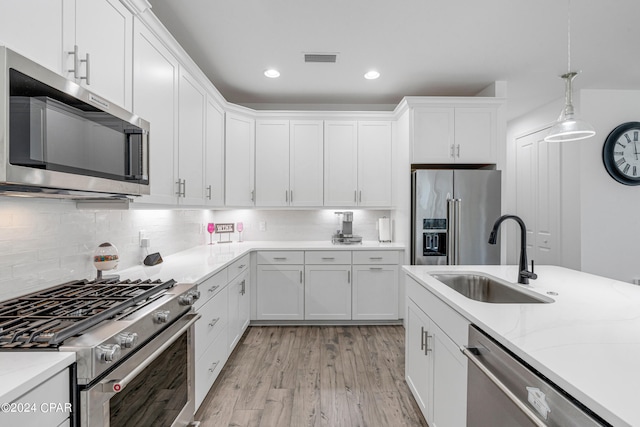 kitchen featuring light hardwood / wood-style floors, sink, white cabinets, hanging light fixtures, and high quality appliances