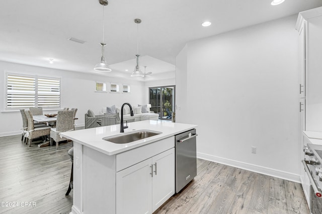 kitchen featuring an island with sink, white cabinets, stainless steel appliances, decorative light fixtures, and sink