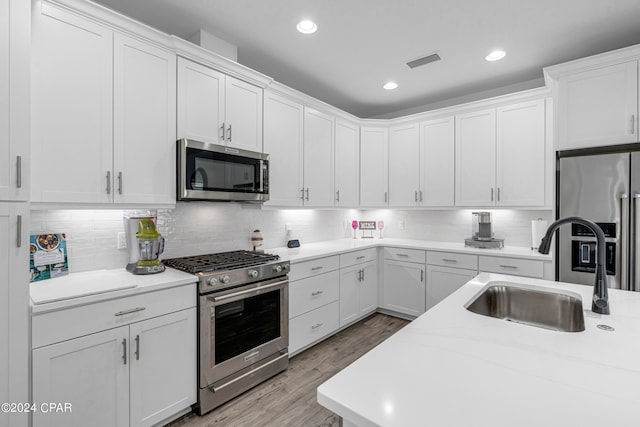 kitchen featuring appliances with stainless steel finishes, light wood-type flooring, sink, and white cabinetry