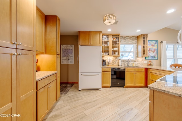 kitchen with light stone counters, a sink, freestanding refrigerator, dishwasher, and tasteful backsplash