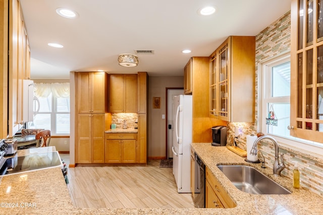 kitchen featuring light wood-style flooring, backsplash, a sink, light stone countertops, and white appliances