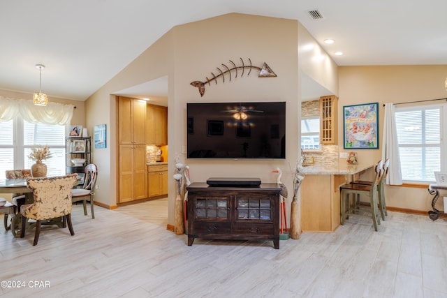 living room with lofted ceiling, light wood-style flooring, and a healthy amount of sunlight