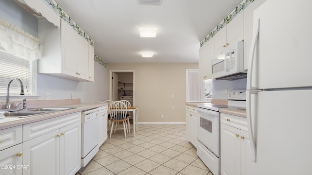 kitchen featuring white appliances, light tile patterned floors, white cabinets, light countertops, and a sink