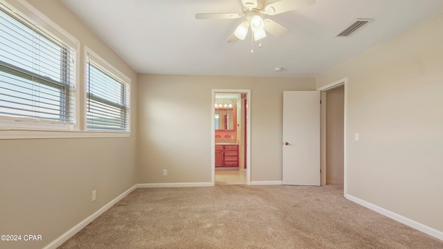 unfurnished bedroom featuring ceiling fan, light carpet, and ensuite bathroom