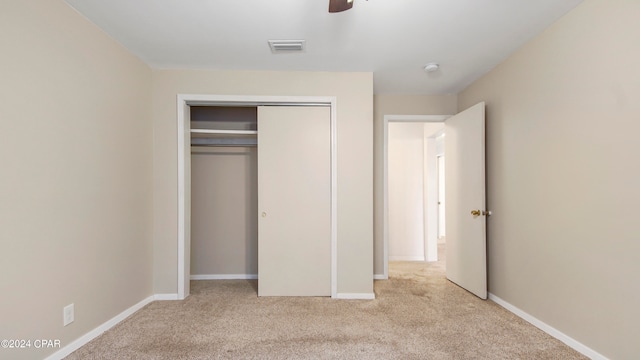 unfurnished bedroom with light carpet, ceiling fan, and a closet