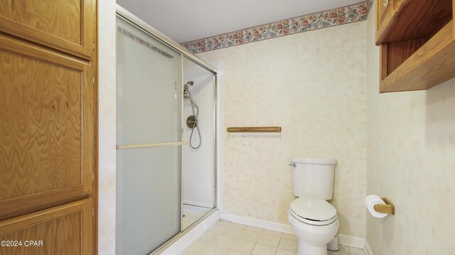 bathroom with toilet, a shower with shower door, and tile patterned floors