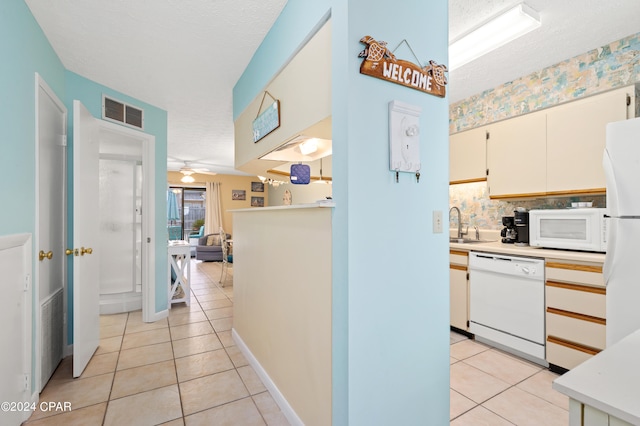 kitchen featuring a textured ceiling, ceiling fan, light tile patterned floors, and white appliances