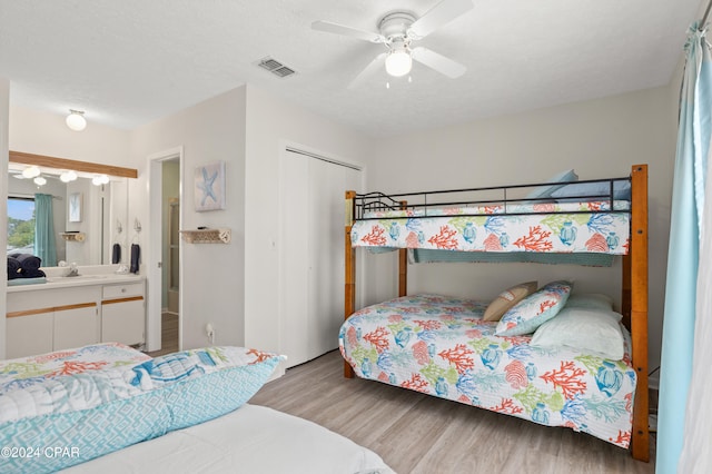 bedroom featuring a textured ceiling, a closet, light hardwood / wood-style floors, sink, and ceiling fan