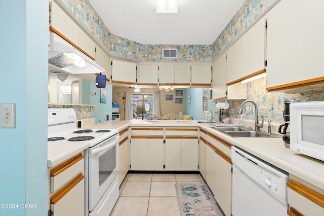 kitchen with white appliances, light tile patterned floors, kitchen peninsula, sink, and white cabinets