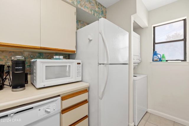 kitchen featuring white cabinets, white appliances, light tile patterned floors, and stacked washer and dryer