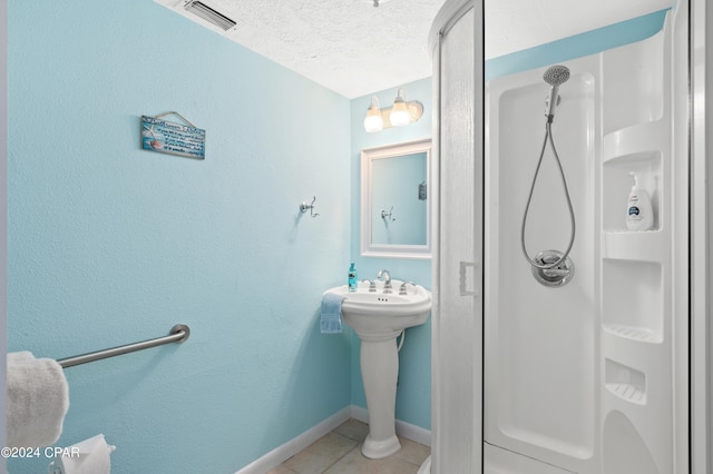 bathroom featuring a textured ceiling, a shower, and tile patterned flooring