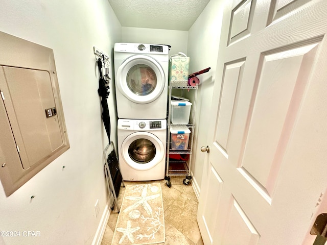 washroom with electric panel, stacked washer and clothes dryer, and a textured ceiling