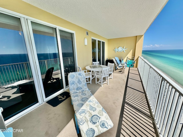 balcony featuring a view of the beach and a water view