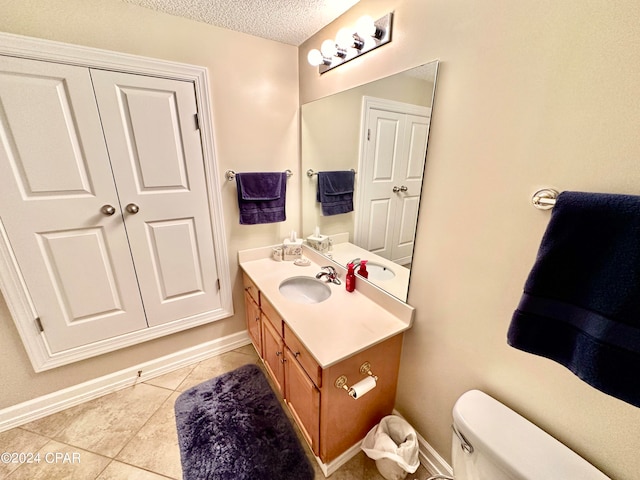 bathroom featuring tile patterned flooring, toilet, a textured ceiling, and vanity