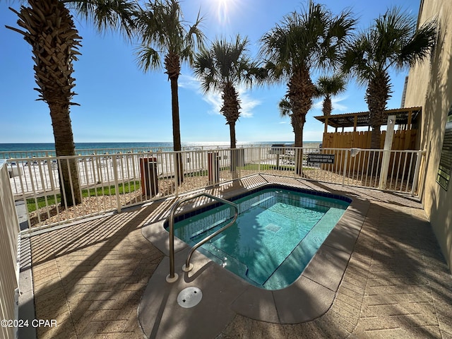 view of pool featuring a view of the beach, a water view, and a patio area