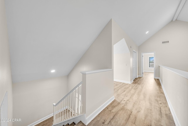 corridor with light hardwood / wood-style flooring and vaulted ceiling