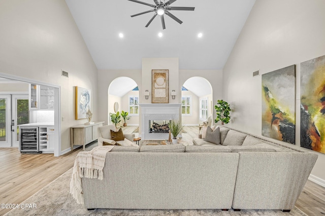 living room with light hardwood / wood-style floors, beverage cooler, ceiling fan, and high vaulted ceiling