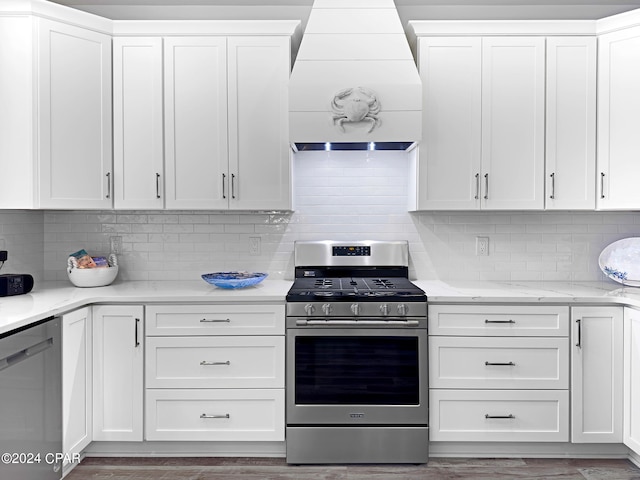 kitchen with appliances with stainless steel finishes, hardwood / wood-style flooring, custom range hood, and white cabinets