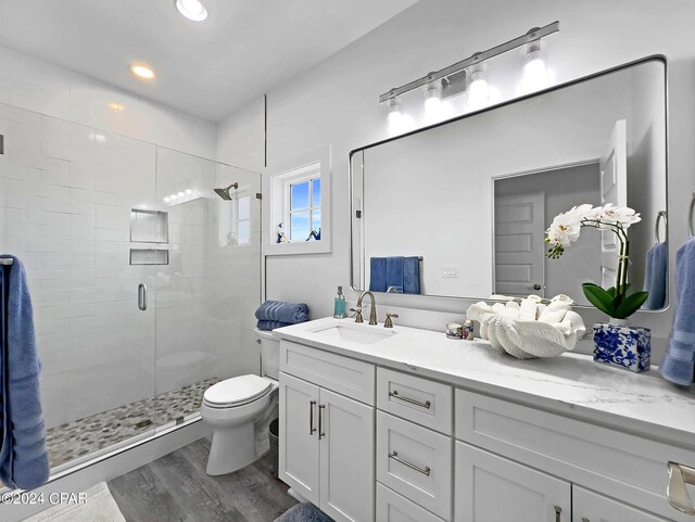 bathroom with vanity, recessed lighting, toilet, a shower stall, and wood finished floors