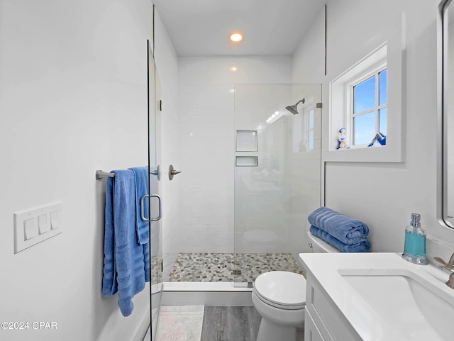 bathroom featuring wood-type flooring, vanity, walk in shower, and toilet