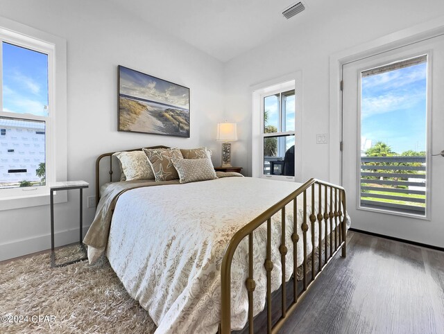 bedroom with baseboards, access to exterior, visible vents, and wood finished floors