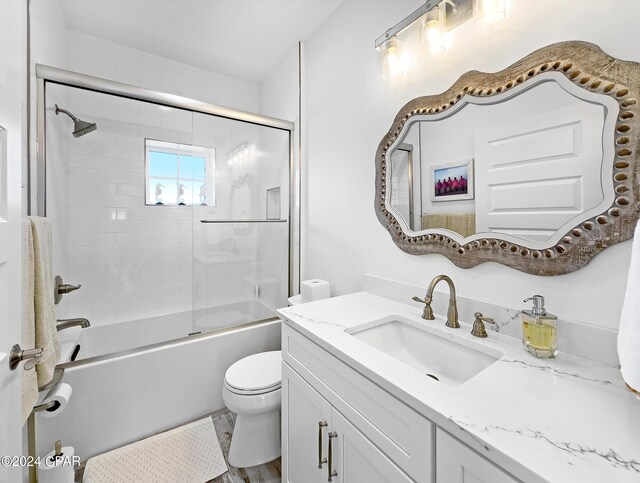 bathroom with enclosed tub / shower combo, toilet, and vanity
