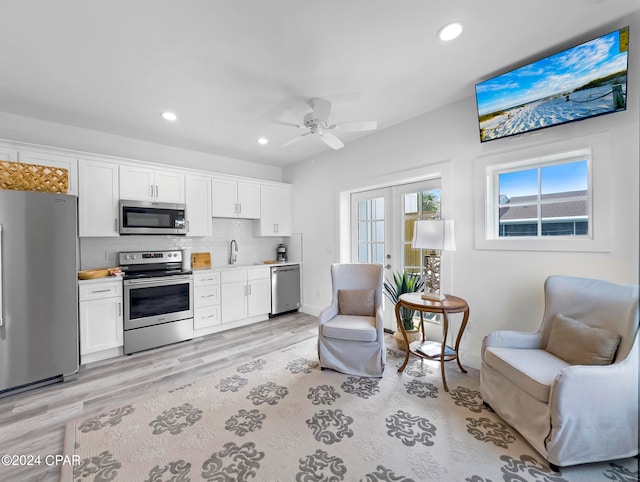 kitchen with appliances with stainless steel finishes, light hardwood / wood-style floors, white cabinetry, and ceiling fan