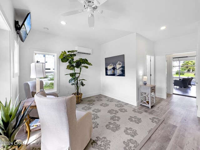 sitting room with ceiling fan, a wall unit AC, light wood finished floors, and recessed lighting