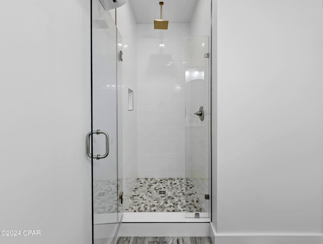 bathroom with wood-type flooring and an enclosed shower