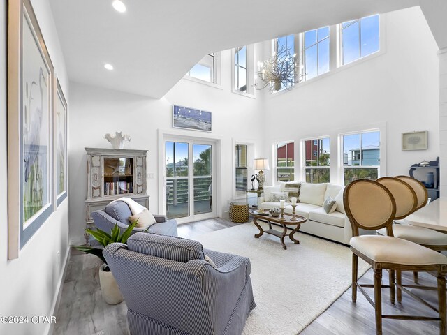 living area with a wealth of natural light, wood finished floors, an inviting chandelier, and recessed lighting