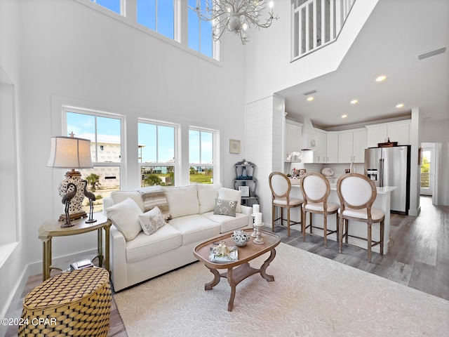 living room featuring a towering ceiling, a notable chandelier, and dark hardwood / wood-style floors