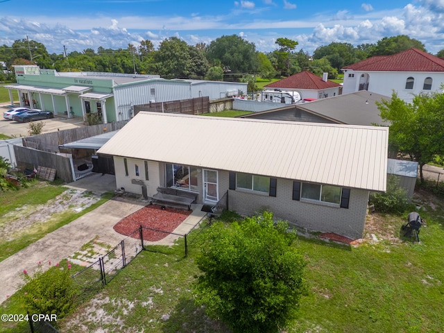 back of house with driveway, metal roof, fence private yard, a yard, and brick siding