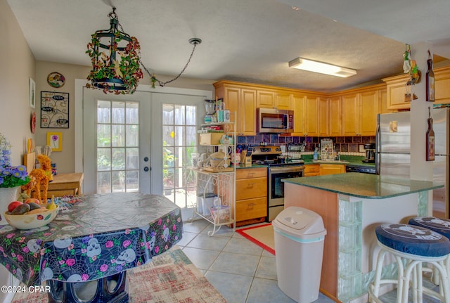 kitchen with french doors, a center island, decorative backsplash, appliances with stainless steel finishes, and light tile patterned flooring